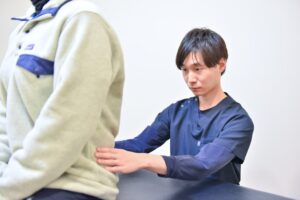 整体施術中の男性整体師と患者様の背中