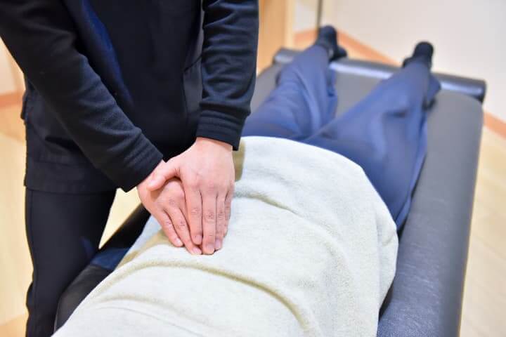 整体施術中の男性整体師の手と患者様の背中