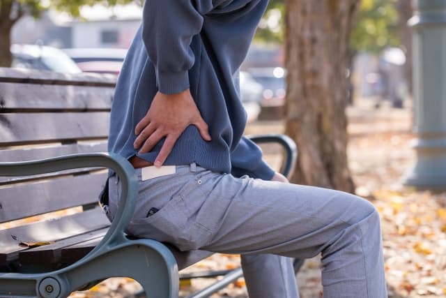 腰を痛そうに押さえる中年男性