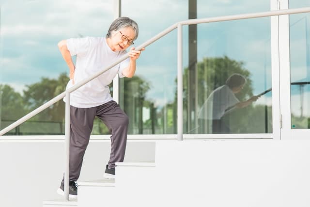 腰を痛そうに押さえる中年女性