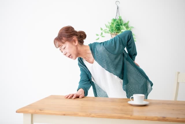 腰を痛そうに押さえる中年女性