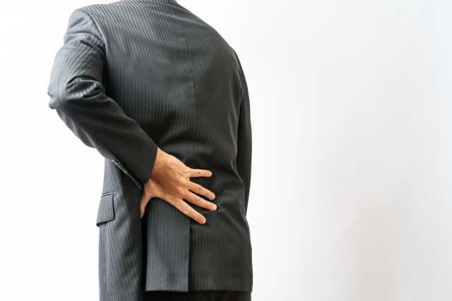 腰を痛そうに押さえる中年男性