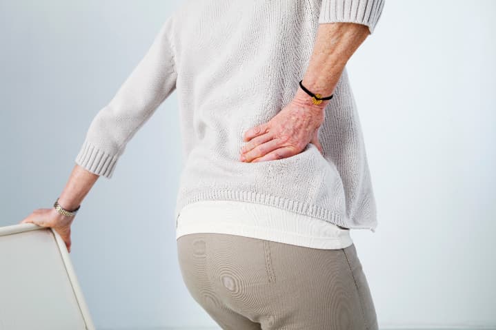 腰を痛そうに押さえる中年女性