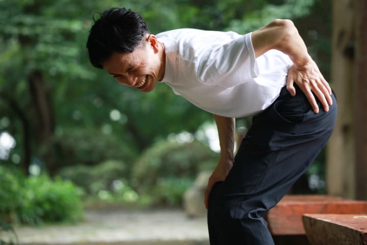 腰を痛そうに押さえるえる男性